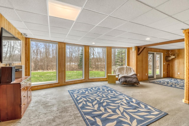 unfurnished room with carpet, a drop ceiling, and wooden walls