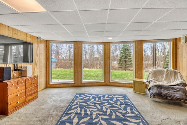 interior space with concrete flooring, a drop ceiling, and wood walls