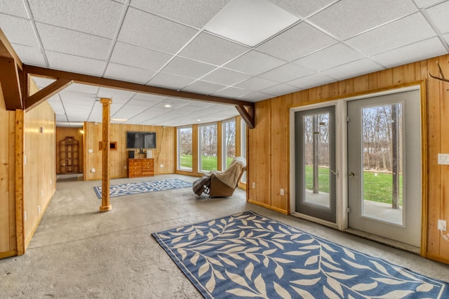 interior space featuring a paneled ceiling and wooden walls