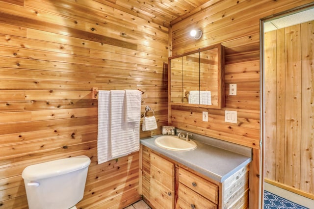 bathroom featuring vanity, toilet, and wood walls