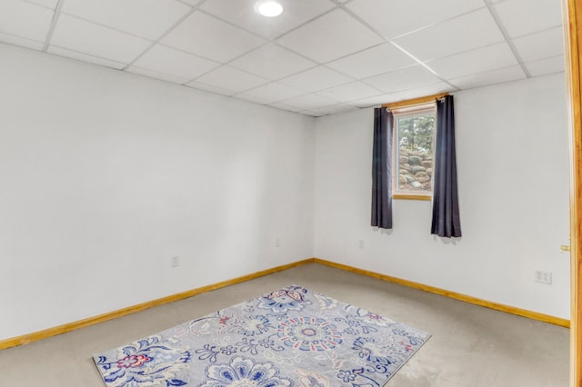 carpeted empty room featuring baseboards and a drop ceiling