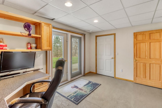 office area featuring baseboards, a drop ceiling, and light carpet