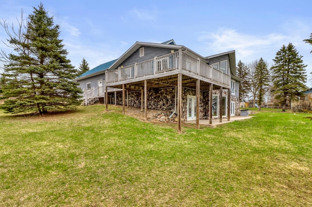 rear view of house with stone siding, a deck, a patio area, a lawn, and stairway