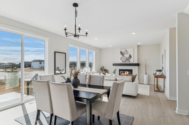 10124 Arrowwood Trl, Woodbury, MN 55129 - dining area featuring a chandelier, healthy amount of natural light, light wood-style floors, a glass covered fireplace, and recessed lighting