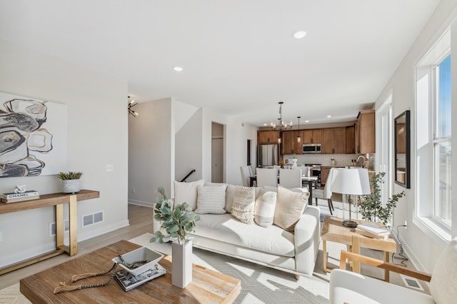 10124 Arrowwood Trl, Woodbury, MN 55129 - living room featuring a chandelier, healthy amount of natural light, recessed lighting, light wood-style flooring, and baseboards