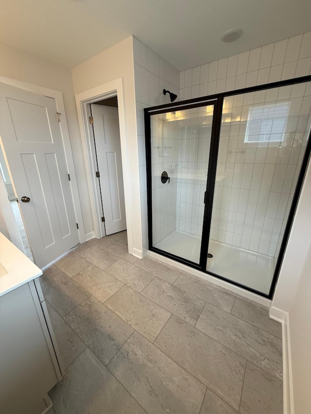 10124 Arrowwood Trl, Woodbury, MN 55129 - bathroom featuring a stall shower, vanity, baseboards, and stone tile floors