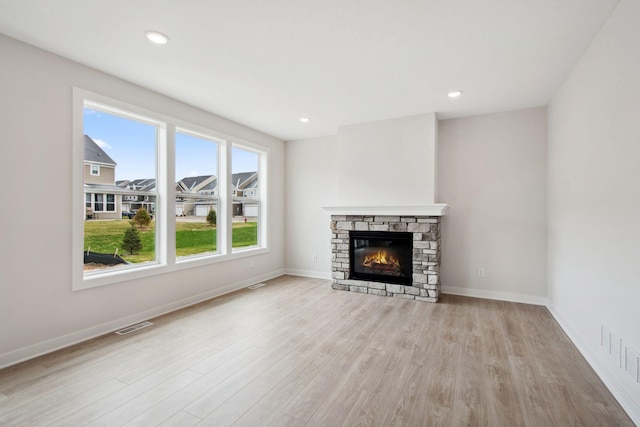 10124 Arrowwood Trl, Woodbury, MN 55129 - unfurnished living room featuring a stone fireplace, light wood-style flooring, baseboards, and recessed lighting