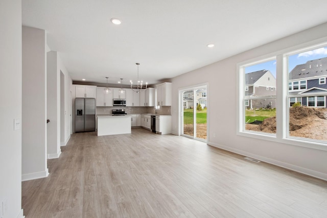 10124 Arrowwood Trl, Woodbury, MN 55129 - unfurnished living room with a chandelier, baseboards, light wood-style flooring, and recessed lighting