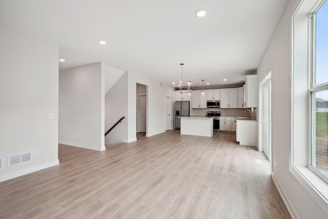 10124 Arrowwood Trl, Woodbury, MN 55129 - unfurnished living room featuring a sink, light wood-type flooring, recessed lighting, baseboards, and a chandelier