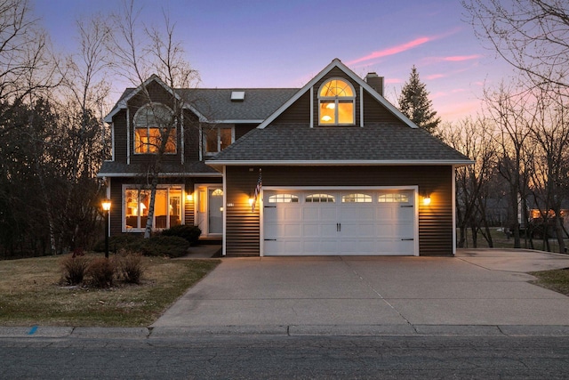 view of front of home featuring roof with shingles, a chimney, concrete driveway, and a garage