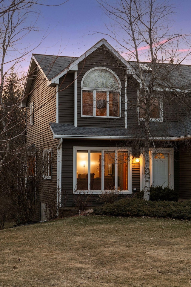 rear view of property featuring a lawn and roof with shingles