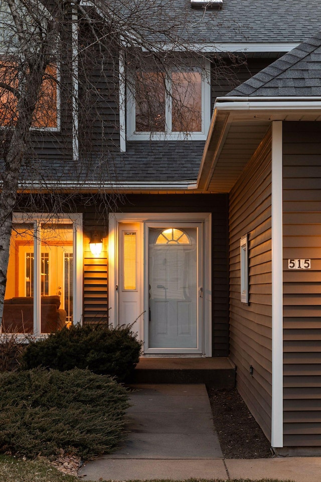 entrance to property featuring roof with shingles