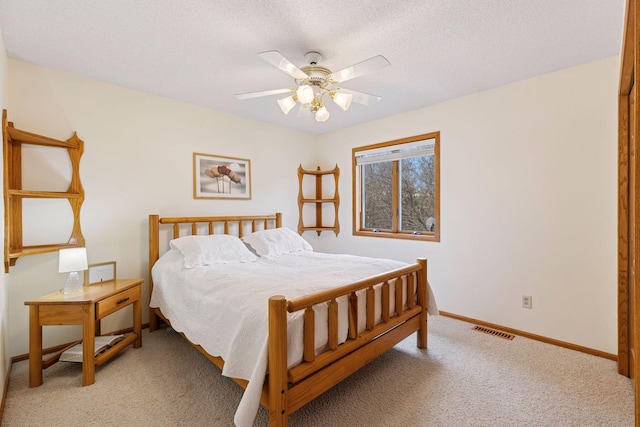 bedroom with baseboards, a textured ceiling, visible vents, ceiling fan, and light colored carpet