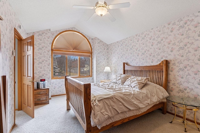 bedroom featuring baseboards, a textured ceiling, vaulted ceiling, wallpapered walls, and light colored carpet