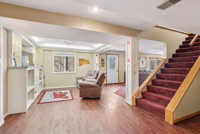 living room with visible vents, decorative columns, wood finished floors, and stairs