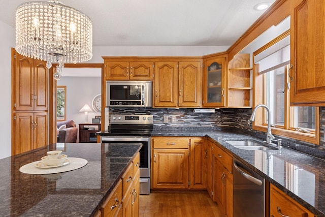 kitchen with stainless steel appliances, brown cabinetry, a sink, and decorative backsplash