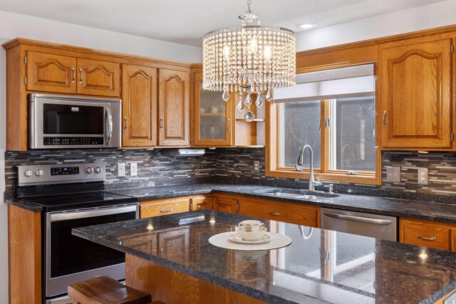 515 Greaton Rd, New Richmond, WI 54017 - kitchen with stainless steel appliances, brown cabinetry, dark stone countertops, a chandelier, and recessed lighting