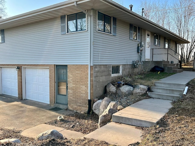view of front of property featuring a garage, brick siding, central air condition unit, and concrete driveway