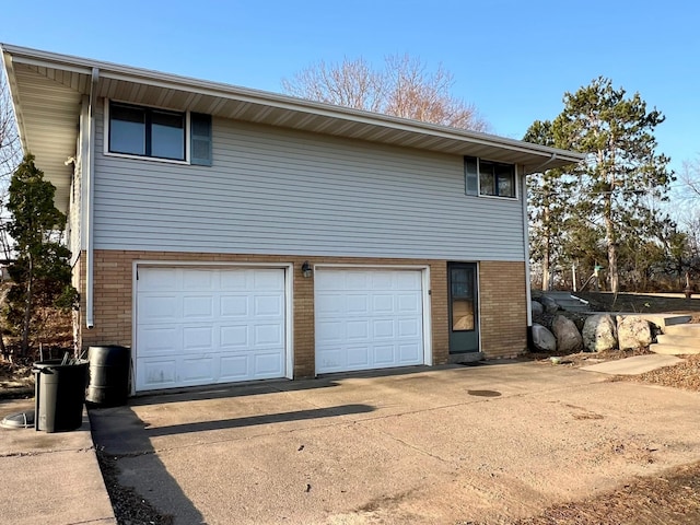 view of home's exterior with concrete driveway, an attached garage, and brick siding