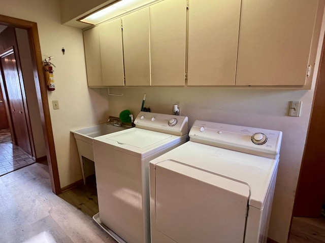 laundry area featuring washing machine and clothes dryer, baseboards, light wood-style floors, and cabinet space