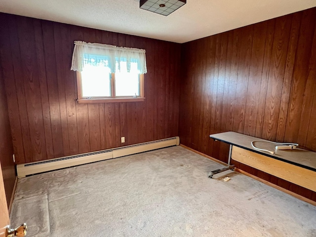 carpeted empty room with baseboard heating and wooden walls