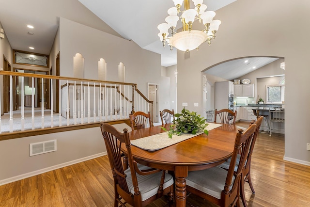 13162 Glenhaven Ave, Apple Valley, MN 55124 - dining room featuring arched walkways, light wood-style flooring, stairway, a chandelier, and high vaulted ceiling