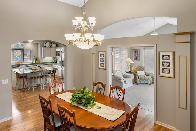 13162 Glenhaven Ave, Apple Valley, MN 55124 - dining space with arched walkways, vaulted ceiling, light wood finished floors, a chandelier, and baseboards