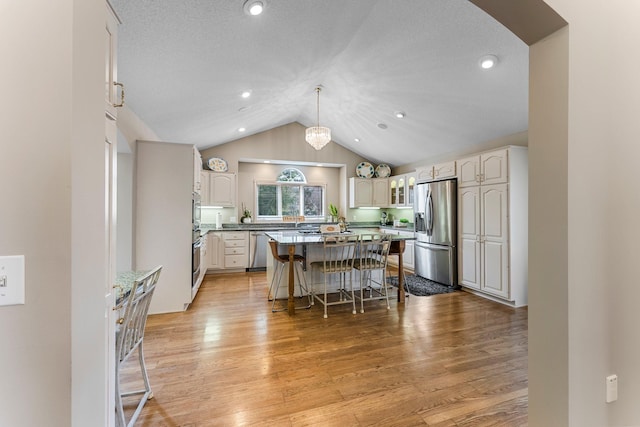 13162 Glenhaven Ave, Apple Valley, MN 55124 - kitchen featuring appliances with stainless steel finishes, a breakfast bar, vaulted ceiling, a center island, and light wood-type flooring