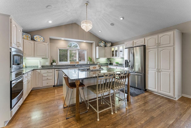 13162 Glenhaven Ave, Apple Valley, MN 55124 - kitchen with appliances with stainless steel finishes, a kitchen breakfast bar, a kitchen island, vaulted ceiling, and a sink