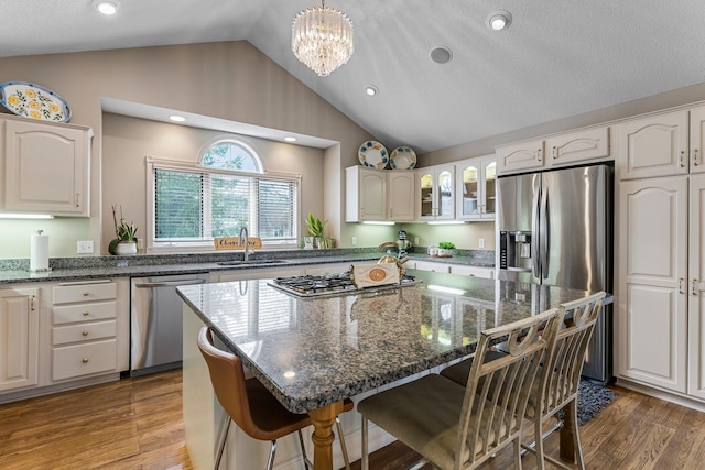 13162 Glenhaven Ave, Apple Valley, MN 55124 - kitchen with appliances with stainless steel finishes, a sink, a kitchen breakfast bar, glass insert cabinets, and a kitchen island