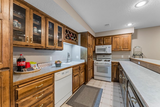 13162 Glenhaven Ave, Apple Valley, MN 55124 - kitchen featuring white appliances, a sink, light flooring, glass insert cabinets, and brown cabinetry