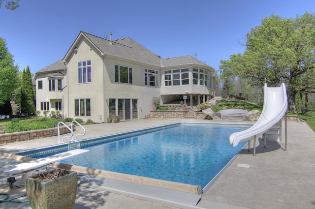 outdoor pool with a water slide, a sunroom, a diving board, a patio, and fence