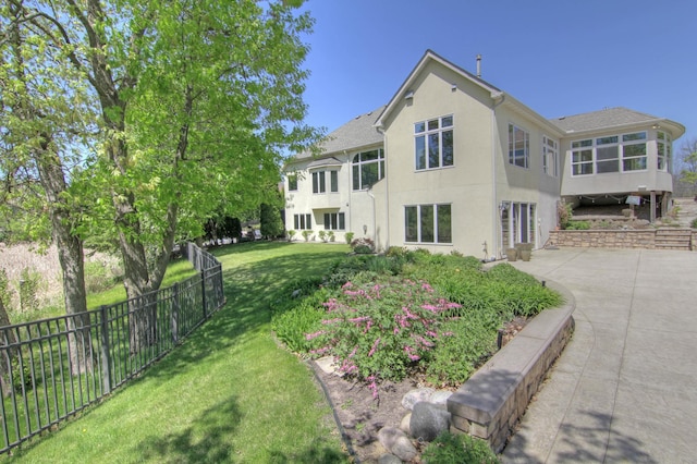rear view of property featuring stucco siding, a sunroom, and a patio