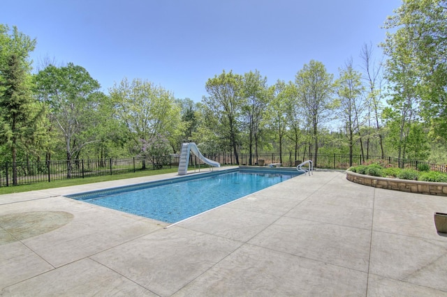 view of pool featuring a water slide, a patio, a fenced backyard, and view of scattered trees