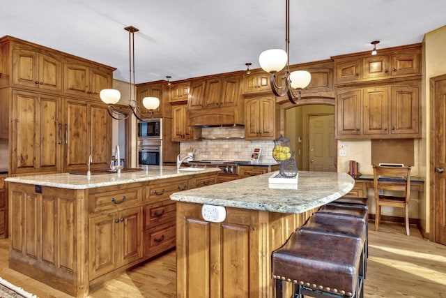 kitchen with a kitchen island with sink, appliances with stainless steel finishes, and brown cabinetry