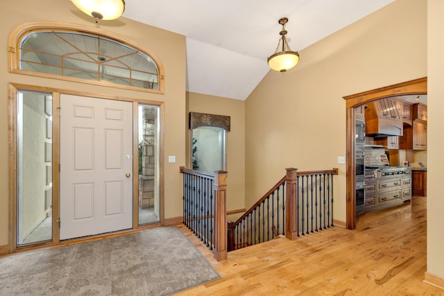 entrance foyer featuring light wood finished floors, lofted ceiling, and baseboards
