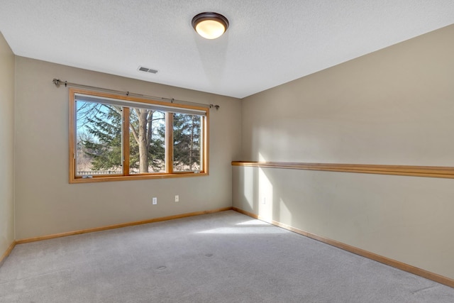 spare room featuring carpet, baseboards, and a textured ceiling