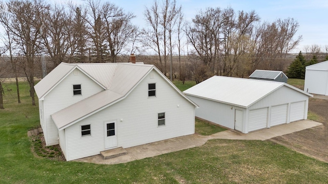 view of home's exterior with a garage, an outdoor structure, a yard, a chimney, and entry steps