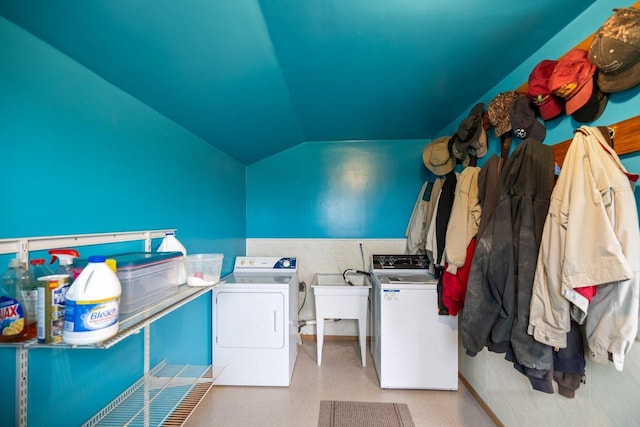 clothes washing area with washer and dryer, a wainscoted wall, laundry area, and a sink