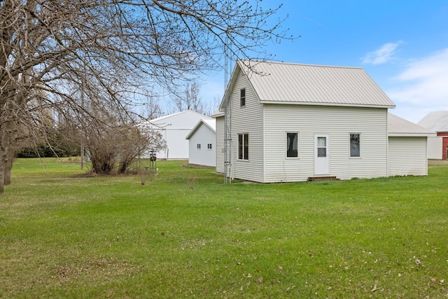 rear view of property with metal roof and a lawn