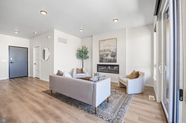 living room with recessed lighting, baseboards, visible vents, and light wood-style floors
