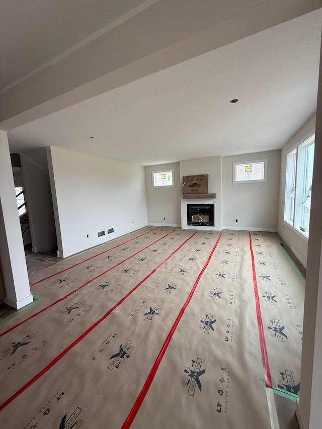 10155 Arrowwood Trl, Woodbury, MN 55129 - unfurnished living room featuring plenty of natural light, a glass covered fireplace, baseboards, and a textured ceiling