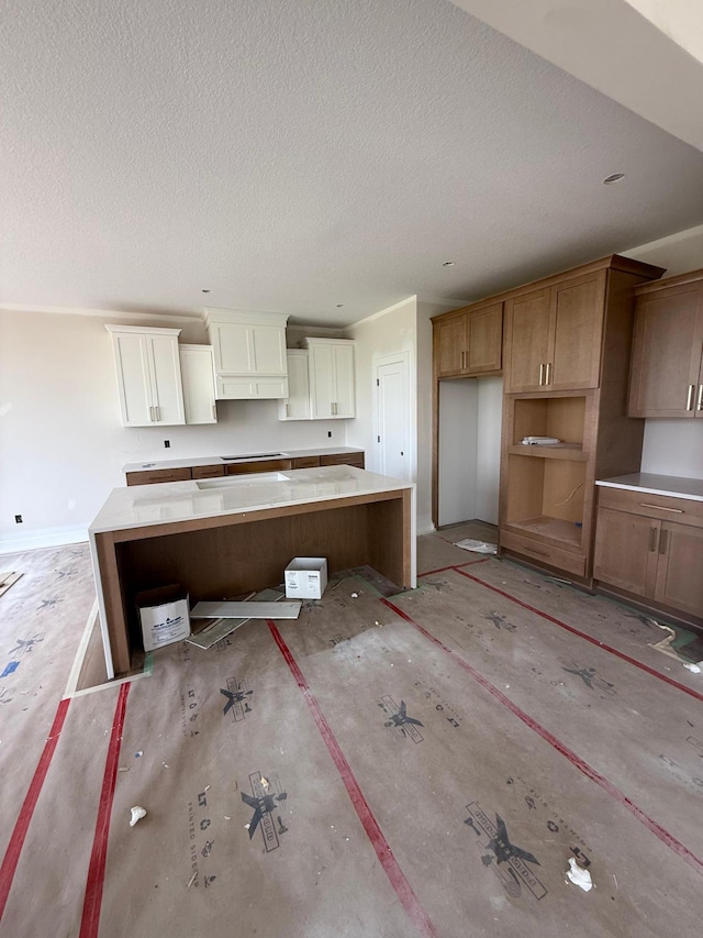 10155 Arrowwood Trl, Woodbury, MN 55129 - kitchen featuring a textured ceiling, a kitchen island, baseboards, and cooktop
