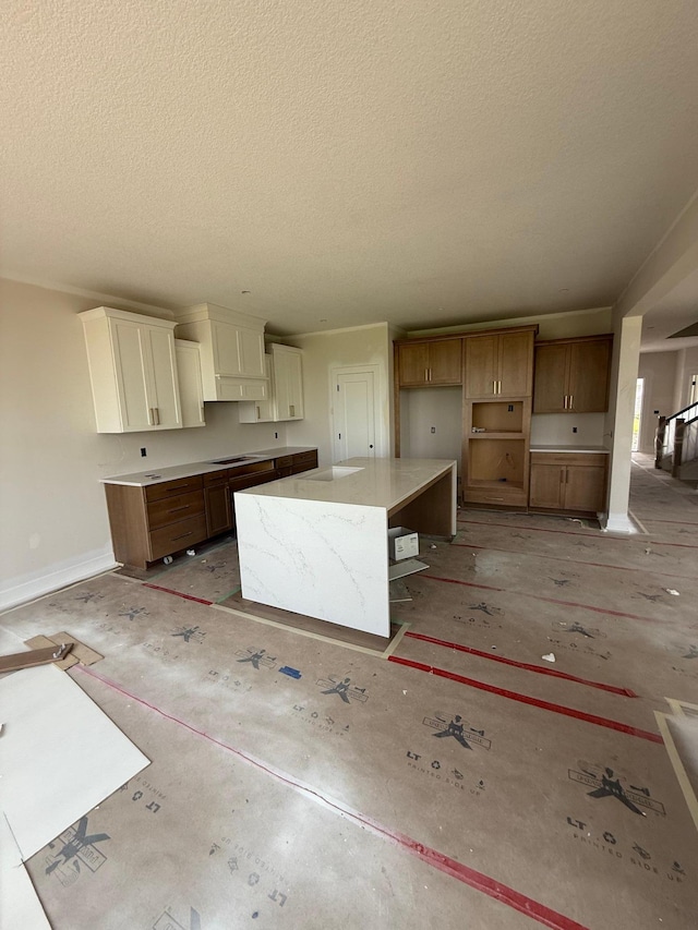 10155 Arrowwood Trl, Woodbury, MN 55129 - kitchen featuring a textured ceiling, a center island, white cabinets, and baseboards