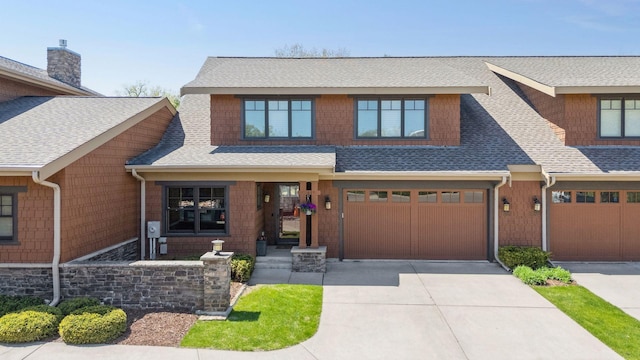 view of front of home with concrete driveway, a shingled roof, and an attached garage