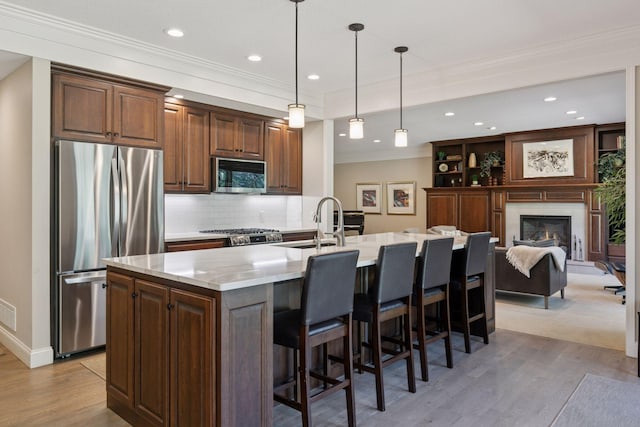 kitchen with a breakfast bar, stainless steel appliances, light wood-type flooring, and a sink