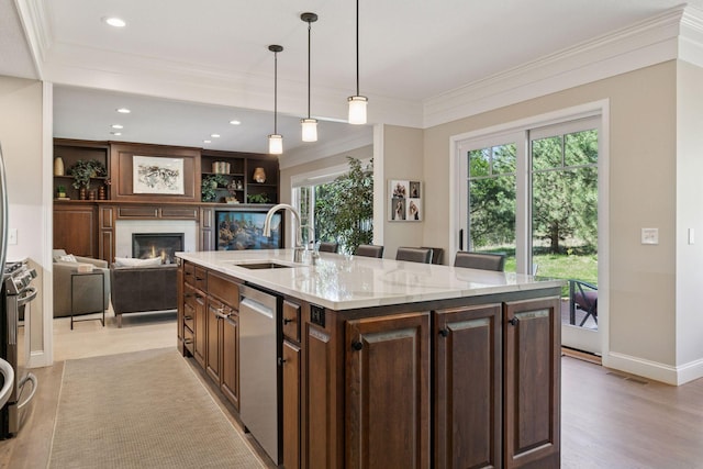 kitchen with dark brown cabinets, a sink, a lit fireplace, crown molding, and light stone countertops