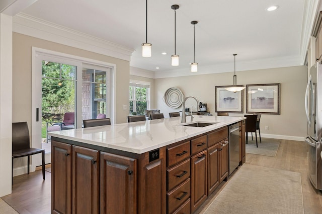 kitchen with light wood finished floors, ornamental molding, stainless steel appliances, and a sink