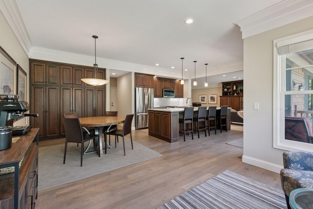 dining room featuring crown molding, baseboards, light wood finished floors, and recessed lighting