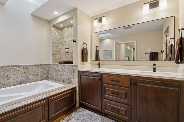 full bathroom featuring double vanity, a garden tub, visible vents, and a sink